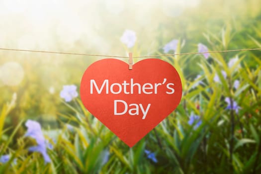 Mothers day message with felt hearts hanging with clothespins over green field background