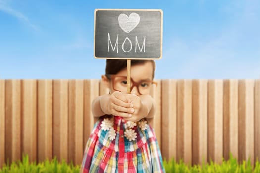 Asian little girl holding chalkboard with Happy mothers day message on green grass
