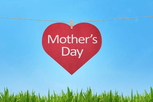 Happy Mothers Day message written on red heart shaped gift tags hanging against a skyline background