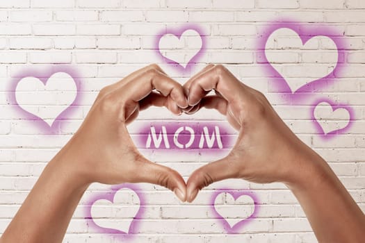People hands in shape of heart with mom text on the white wall