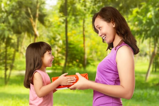 Portrait of happy mother with gift from her daughter in garden. Mothers day concept.