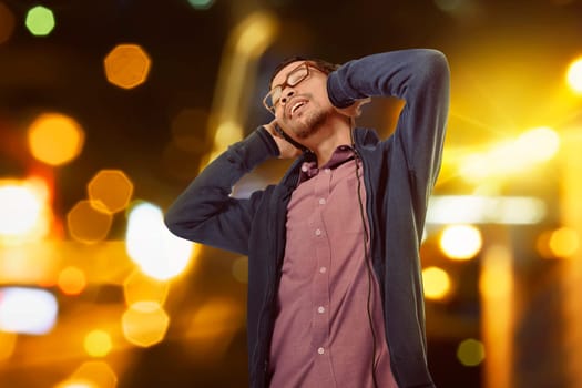 Handsome asian man listening music with handphone against bokeh background