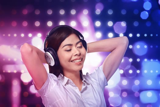 Beautiful asian woman listening music in headphone on blurred light background
