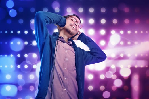 Stylish asian man in headphones listening to music with bokeh background