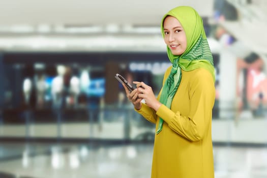 Pretty asian muslim female with mobile phone on the mall