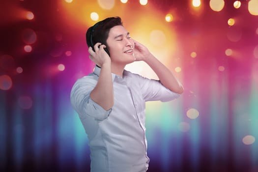 Cheerful asian man enjoying his favorite music in headphones with bokeh background