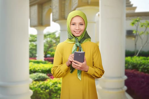 Beautiful asian muslim woman using mobile phone in the park