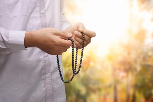 Hand of muslim person pray using prayer beads with abstract background
