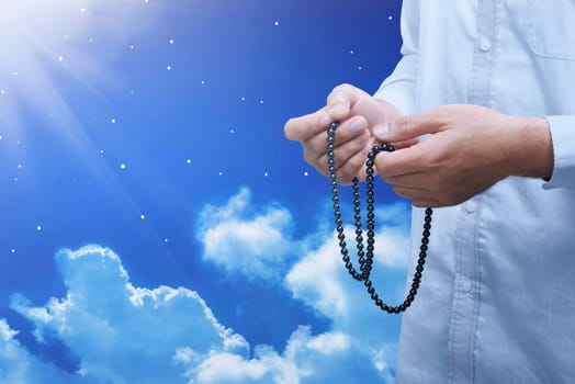Hands of muslim person with prayer beads in hand praying over night scene background