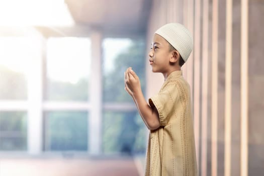 Portrait of asian muslim boy with white cap praying in the mosque