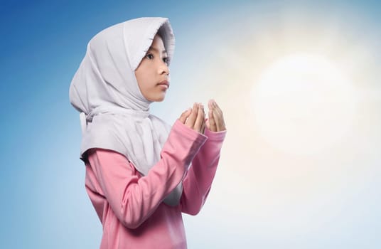 Little asian muslim girl praying to god over sunlight background