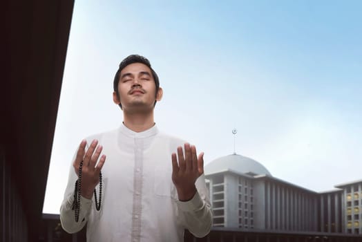 Handsome asian muslim man praying with beads on the mosque