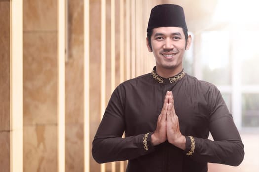 Cheerful asian muslim man praying to god in the mosque