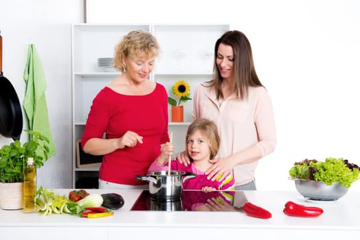woman with daughter and grandchild together cooking together in the kitchen
