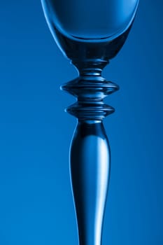 Detailed view of the middle part of a champagne glass with brightness gradient in the background  toned blue.