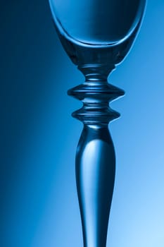 Detailed view of the middle part of a champagne glass with brightness gradient in the background  toned blue.