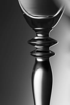 Detailed view of the middle part of a champagne glass with brightness gradient in the background  monochrome.