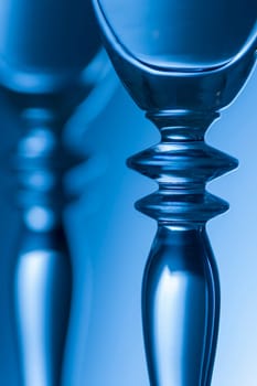 Detailed view of the middle parts of two champagne glasses Brightness running background shaded blue. The focus is on the front glass.