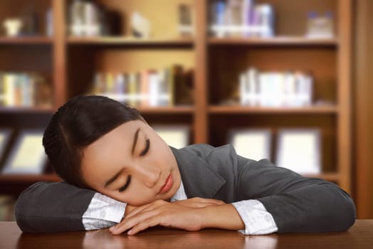 Young tired asian woman sleeping on desk at office