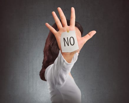 Side view of asian woman showing NO note on her hand against black wall background