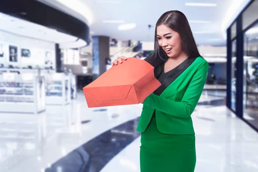 Young asian business woman opening her shopping bag in the mall