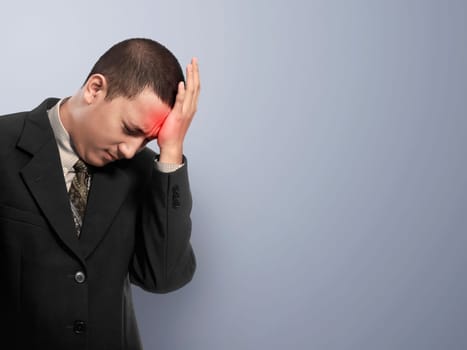 Portrait of asian businessman with headache over gray background
