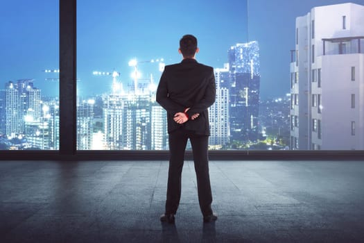 Back view of asian businessman looking the city from the office