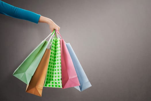 People hand holding colorful shopping bag on grey background