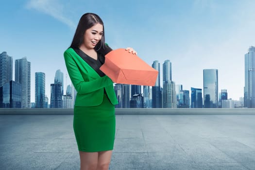 Young asian business woman opening her shopping bag against cityscape background
