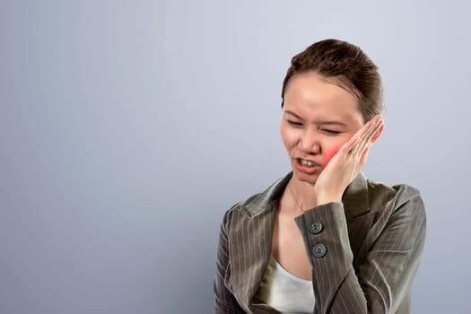 Young asian business woman sensed toothache against gray background