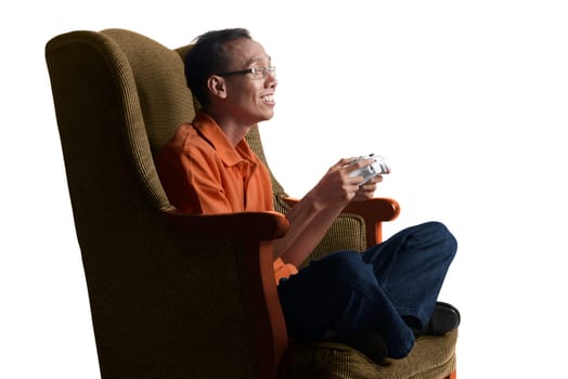 Attractive asian nerd man playing game with gamepad on sofa at home