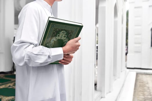 Muslim man hands holding the Koran in the mosque
