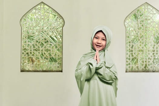 Cheerful asian muslim girl wearing hijab praying in the mosque