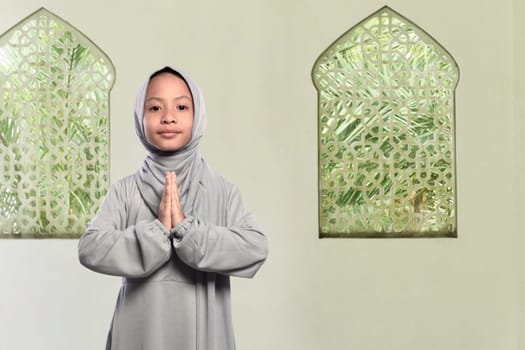 Little asian muslim kid with veil praying to god on the mosque