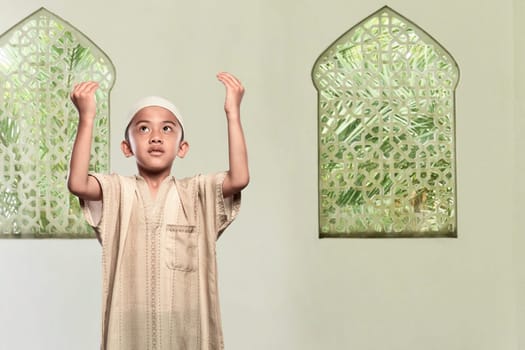 Religious asian muslim child standing praying to god in the mosque
