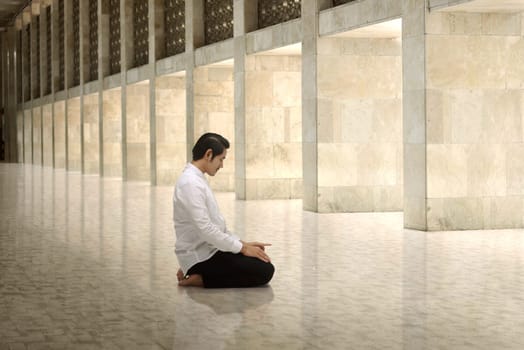 Handsome asian muslim man kneeling and praying to god in the mosque