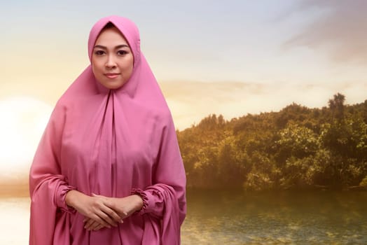 Beautiful asian muslim woman in veil with smiley face standing during sunset