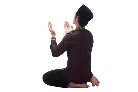Back view of asian muslim man with cap praying isolated over white background