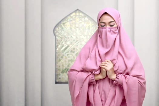 Portrait of asian muslim woman wearing niqab praying on the mosque