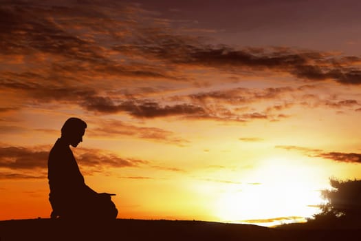 Silhouette of asian muslim man praying on a hilltop at sunset