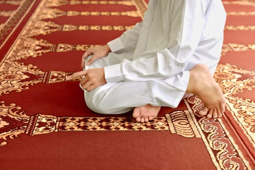 Muslim man kneeling while praying to god on the mosque