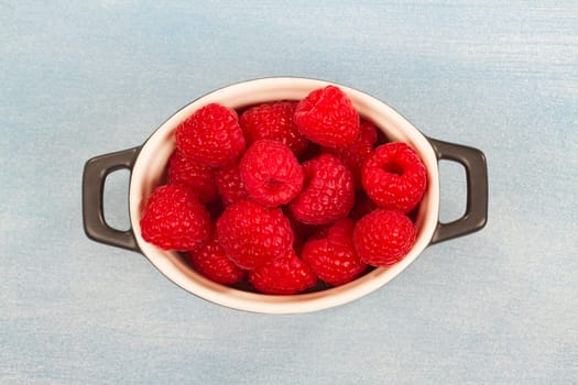 Fresh raspberries on a light blue background