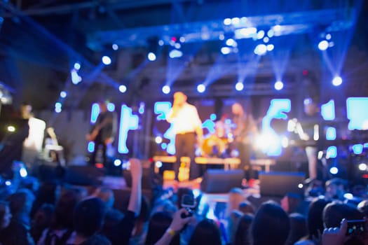The silhouettes of concert crowd in front of bright stage lights. Concert of an abstract rock band