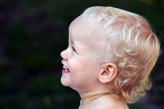 Portrait about a happy little child on green background, profile view.