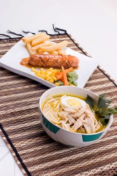 Indonesian traditional chicken soup and sausage served with french fries