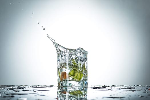 The water splash in glass with kiwi fruits of gray studio color
