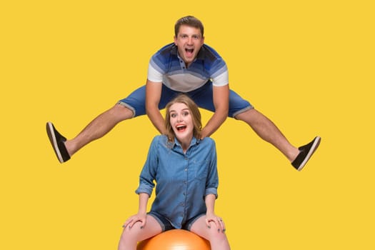 Portrait of a young couple jumping against yellow studio background