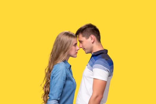 Portrait of a young smiling couple standing against gray studio background and looking at each other