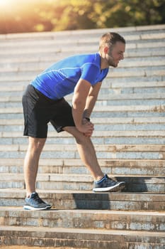 Fit fitness man doing exercises outdoors at park. The man doing exercises. The male sports model jumping outdoor in summer.