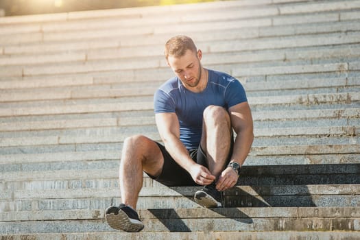 Fit fitness man doing exercises outdoors at park. The man doing exercises. The male sports model jumping outdoor in summer.